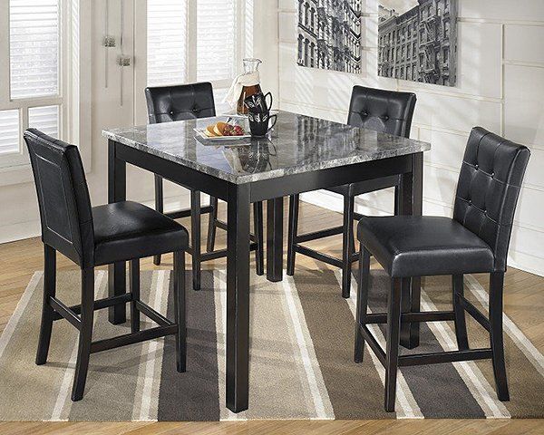A dining room table with four black chairs and a marble top.