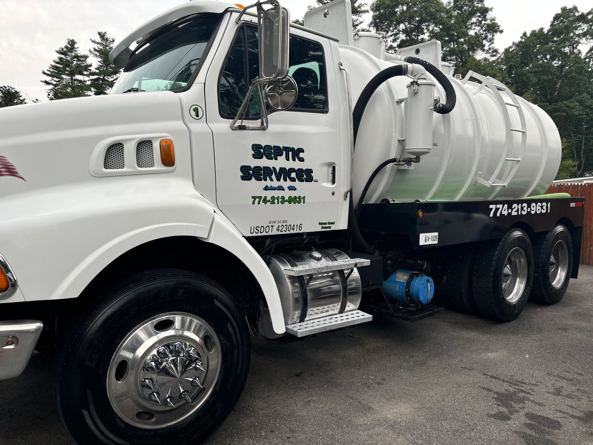 A white septic services truck is parked in a parking lot.