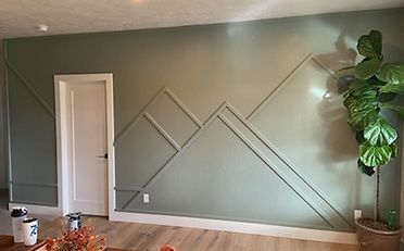 Green accent wall with geometric trim, white door, and potted fiddle-leaf fig.