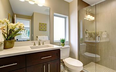 Bathroom with a dark brown vanity, white countertops, a glass shower, and a white toilet.