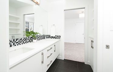 Modern white bathroom with vanity, black and white tile, and doorway.