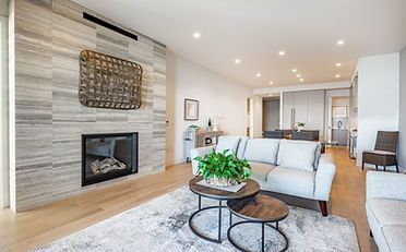 Modern living room with fireplace, sofa, and coffee tables, light wood floors and neutral tones.