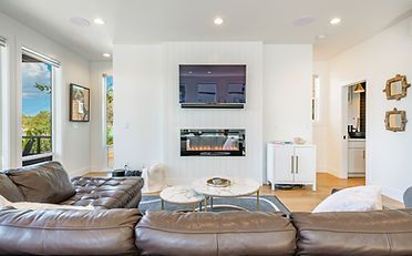 Living room with a leather sofa, fireplace, TV, and white walls.