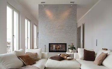 Living room with white sectional sofa, fireplace, and large windows. Gray textured wall.