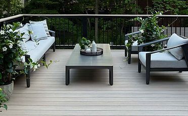 Outdoor deck with modern gray furniture, plants, and coffee table.