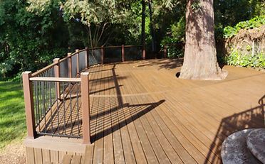 Wooden deck with a tree trunk growing through it, surrounded by railings.