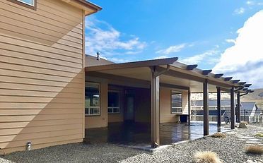 Tan house with brown patio cover and dark grey patio.