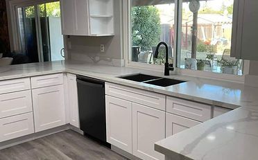 White kitchen with black dishwasher, sink, and faucet; window with view.