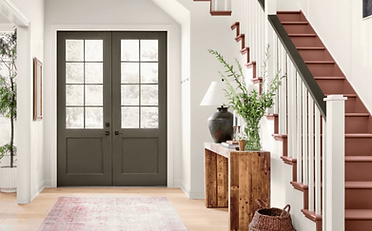 Entryway with olive green doors, terracotta stairs, and a wooden console table with greenery.