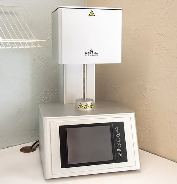 Small lab instrument with white enclosure, black touchscreen, and warning labels on a countertop.
