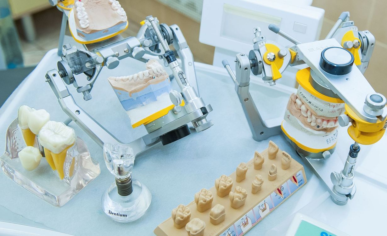 Two white robotic arms assembling dessert pastries on a light blue workstation