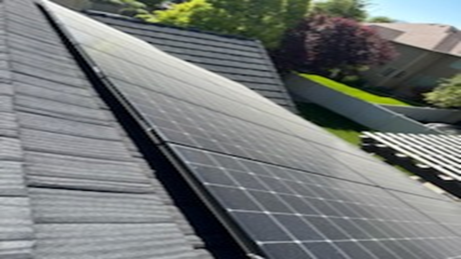 There are many solar panels on the roof of a house.