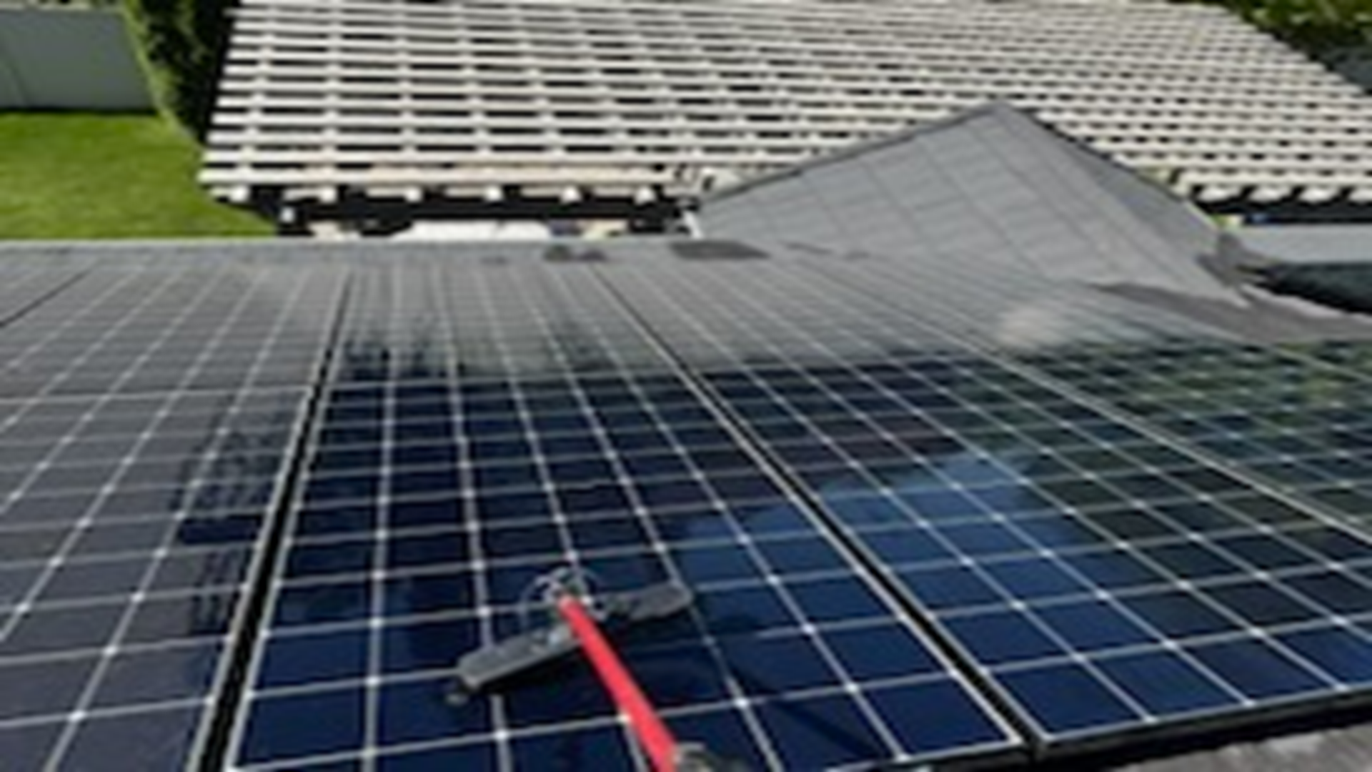 A person is cleaning a solar panel with a broom.