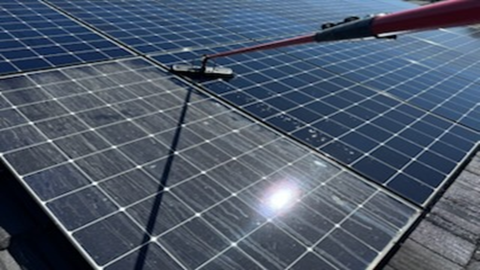 A person is cleaning a solar panel with a broom.