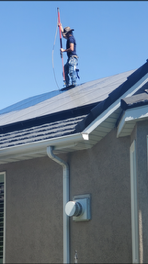 A man is standing on the roof of a house holding a flag
