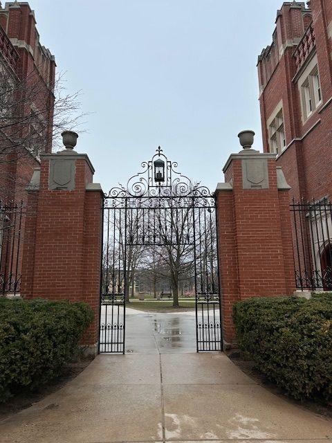 Red brick entrance gate leading to a tree-lined path.