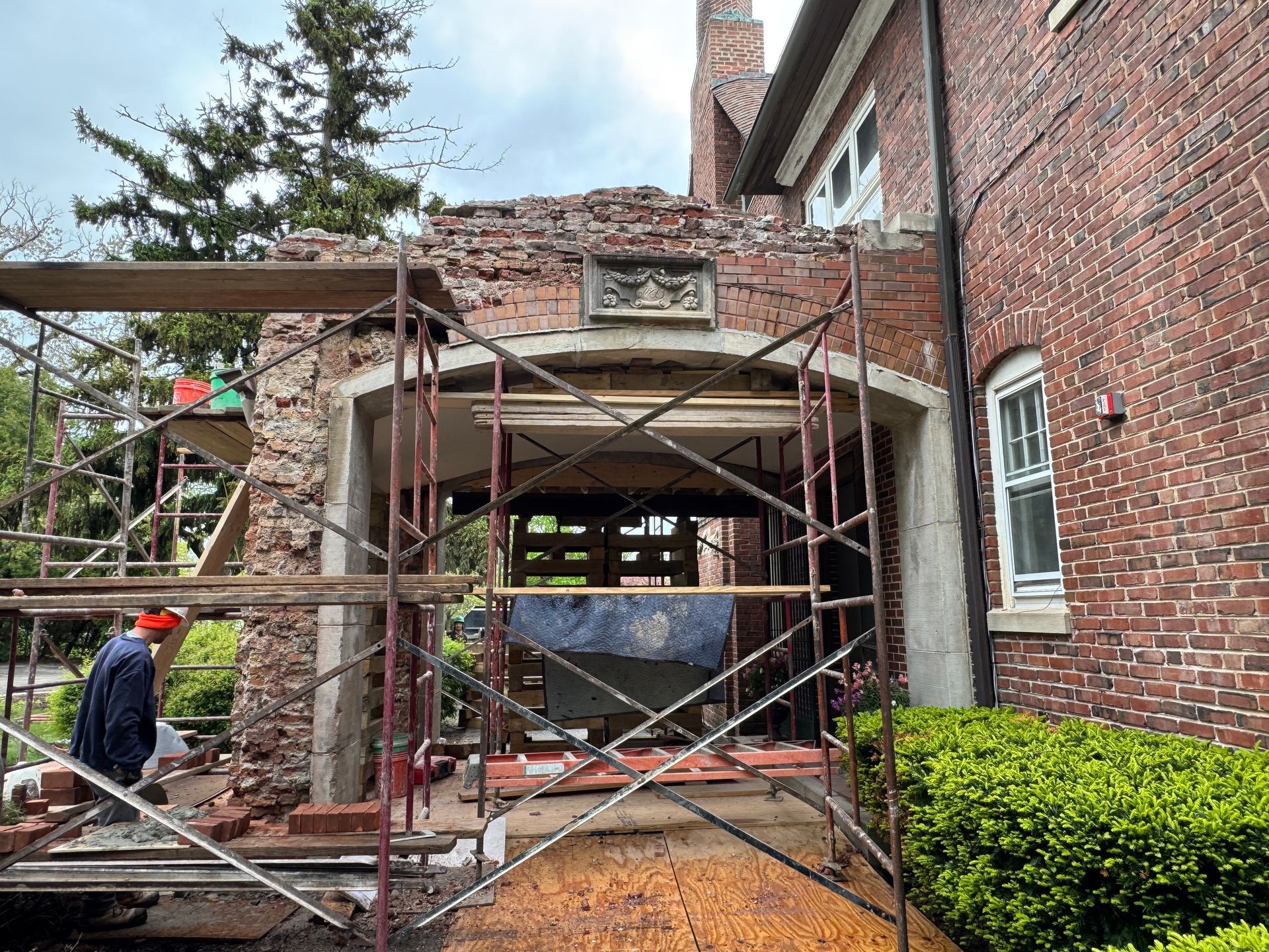 Brick structure under construction, scaffolding, worker, overcast sky.