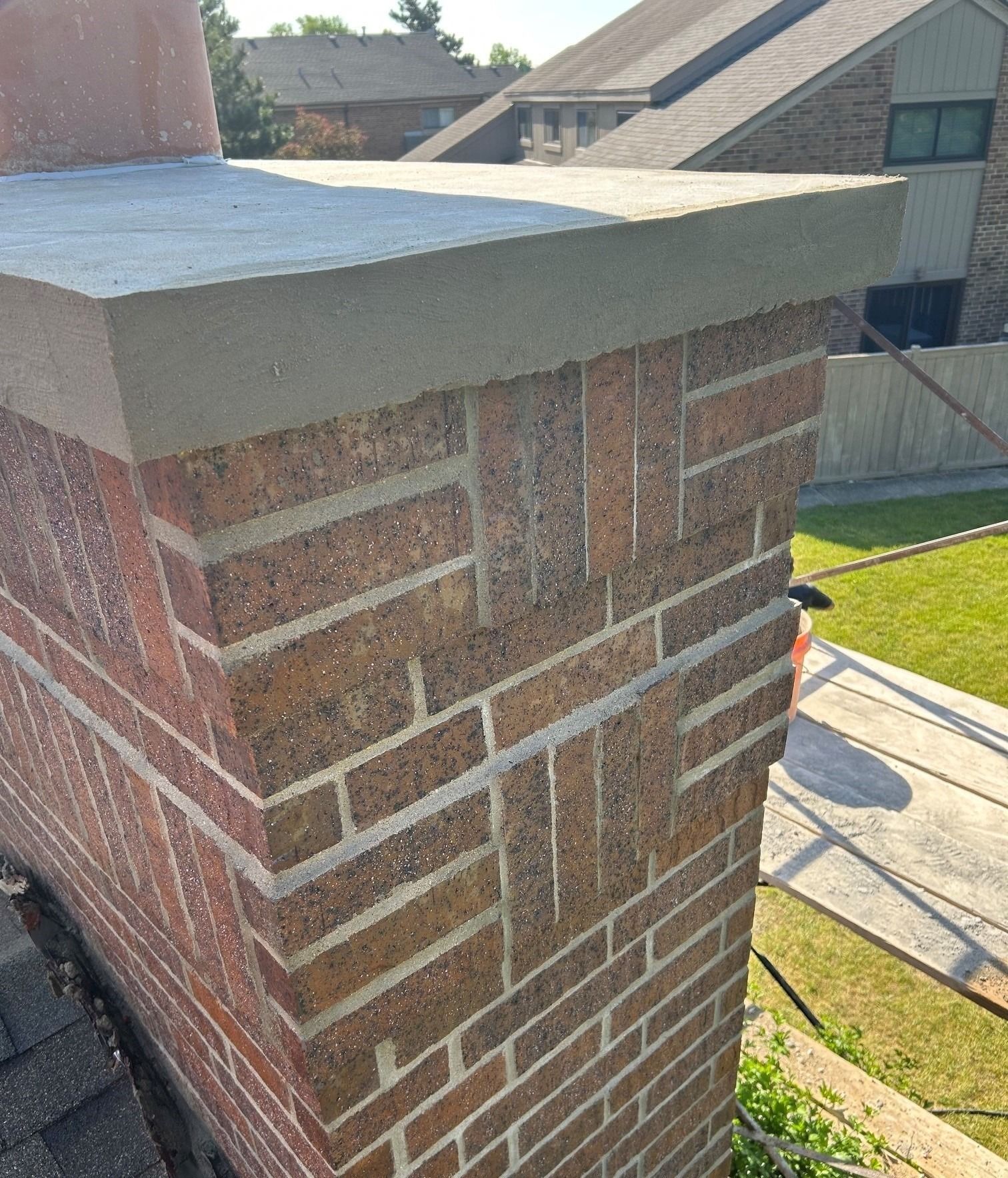 Brick chimney with gray cap on a house roof in daylight