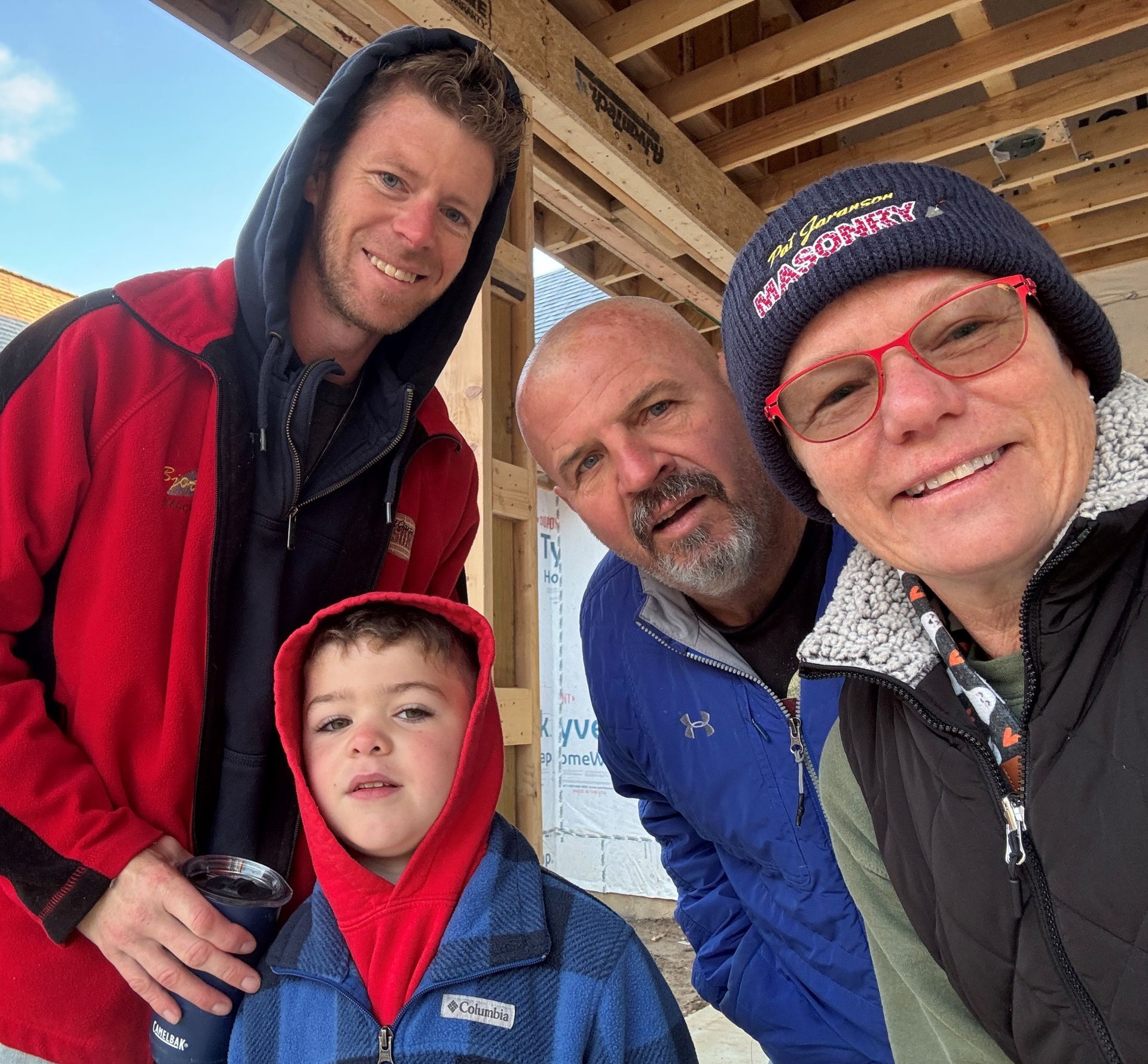 Four people smiling at camera in front of a construction site.
