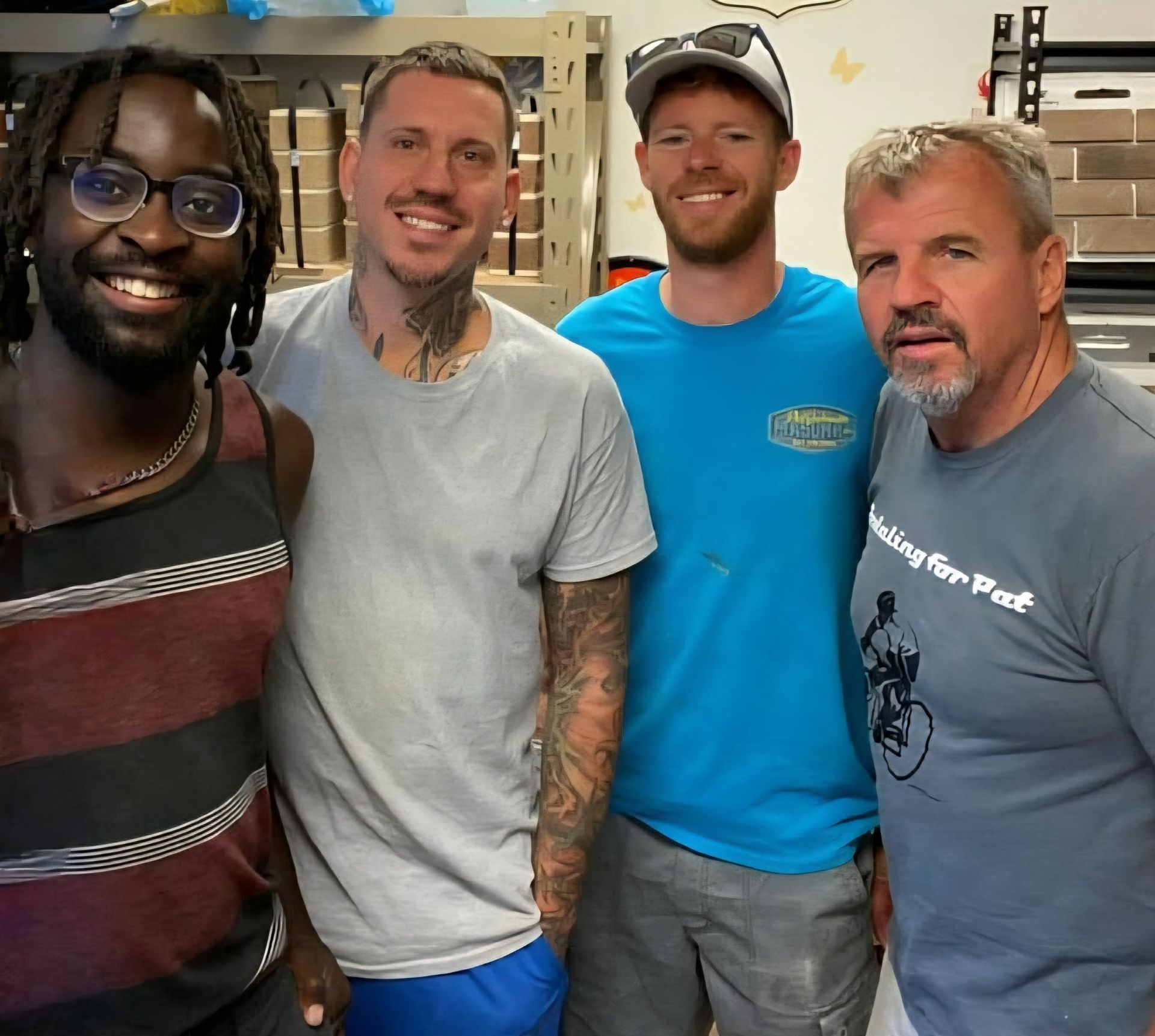 Four men smiling, posing close together indoors.