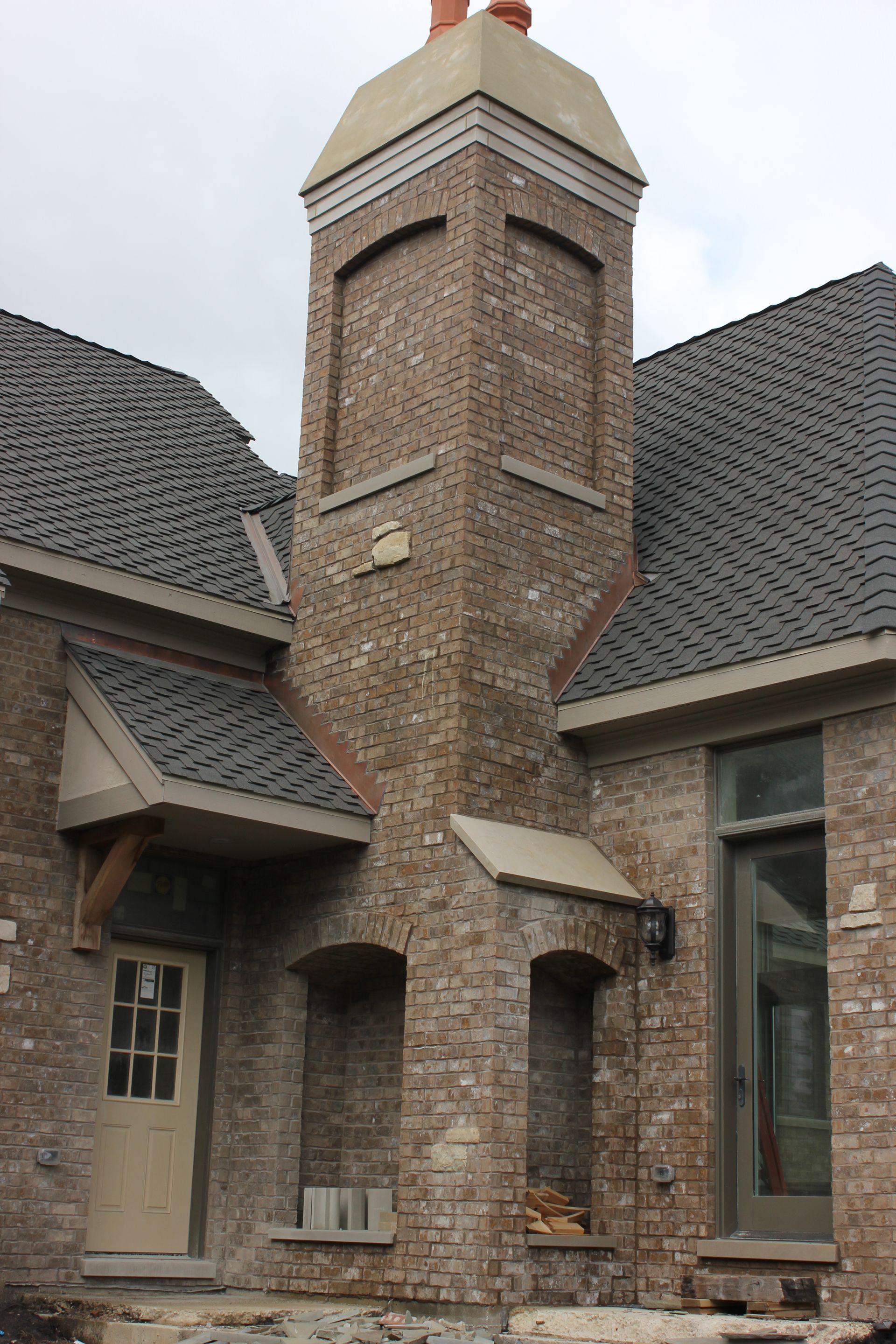 Brick chimney and adjacent home exterior with dark roof and door.