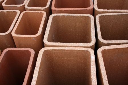 Square terracotta chimney flue sections, close-up view, stacked, varying sizes.