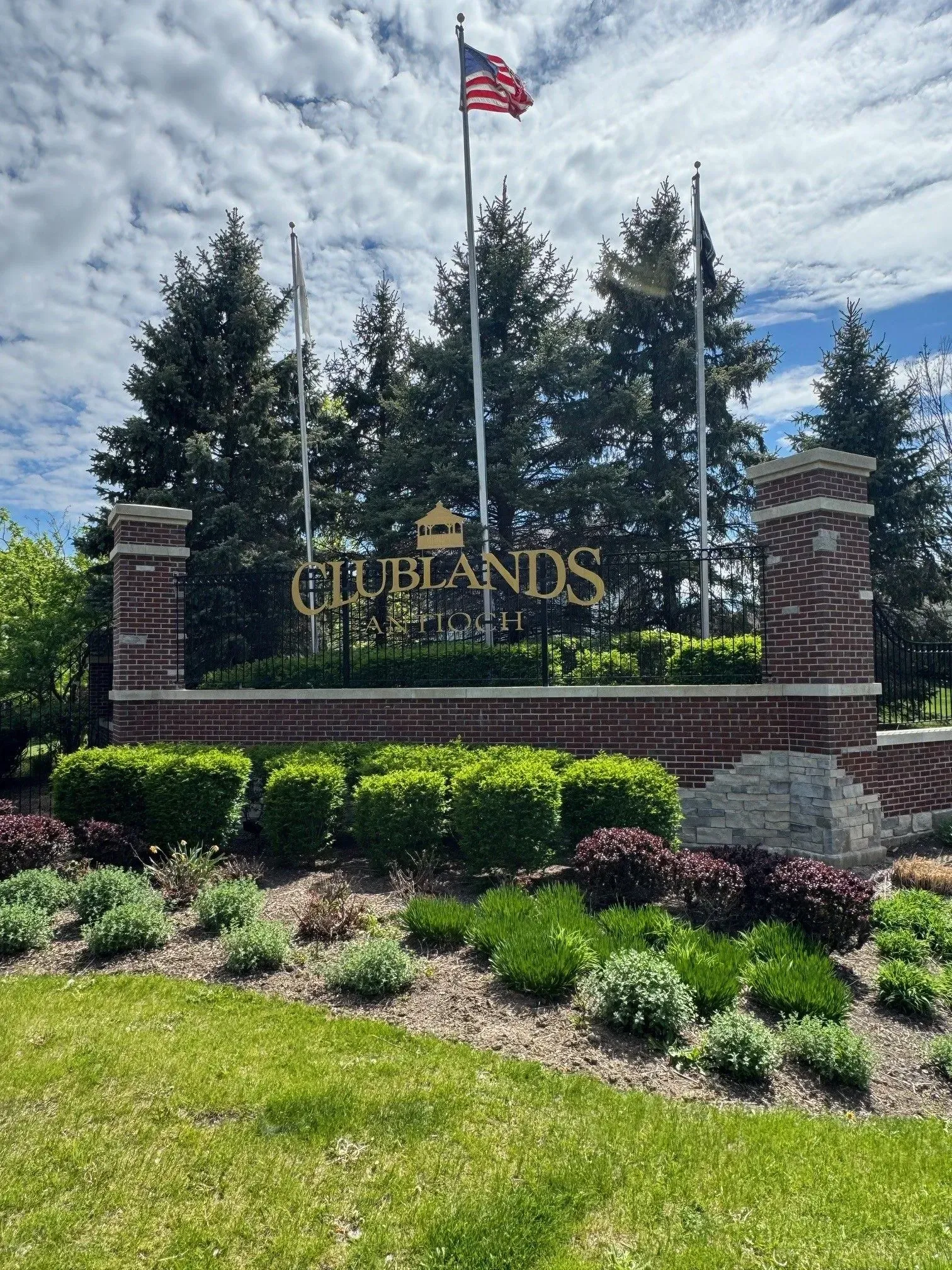 Sign for Clublands residential area with flags and landscaping.
