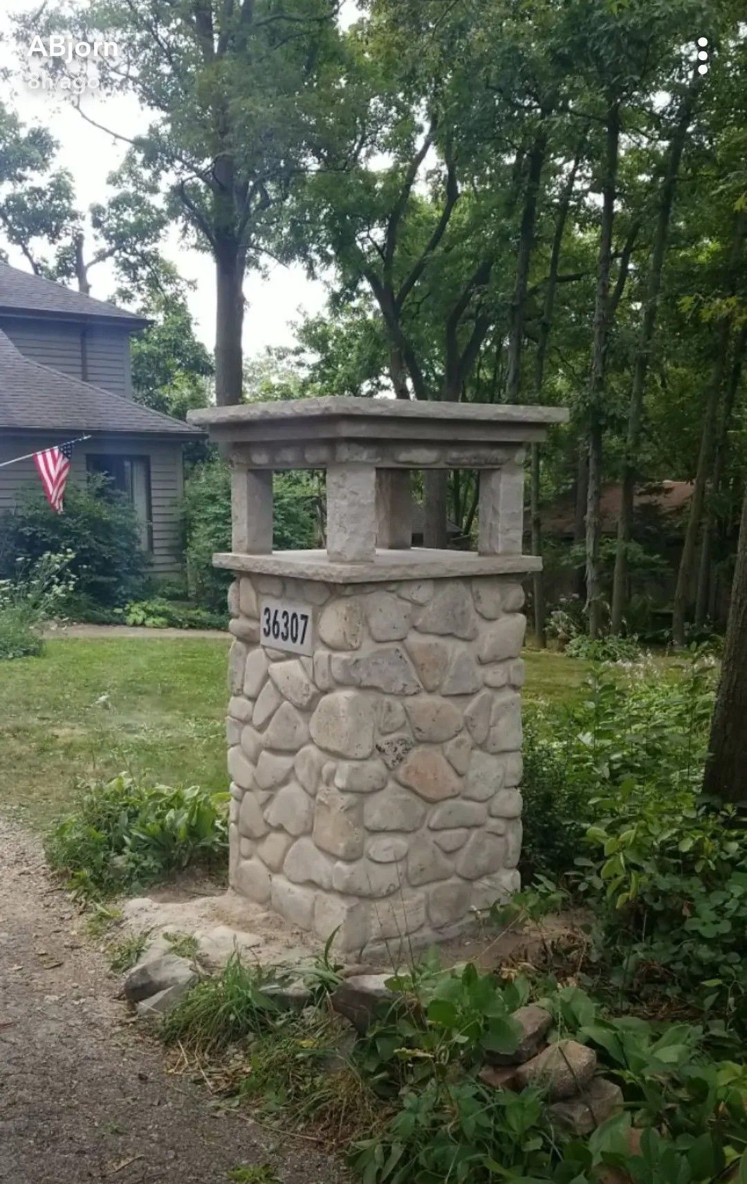 Stone mailbox with address 8001; house and trees in background.
