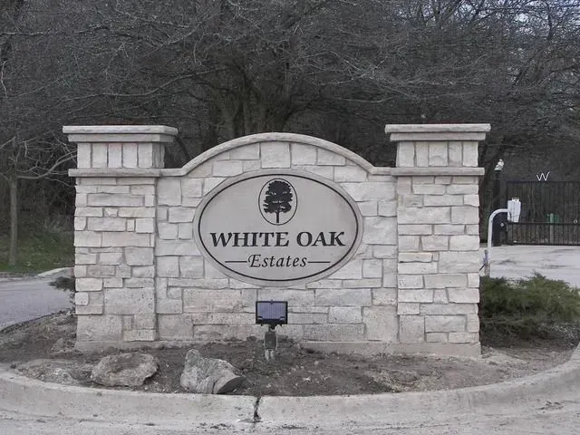 White Oak Estates entrance sign made of light stone with a white oak tree logo.