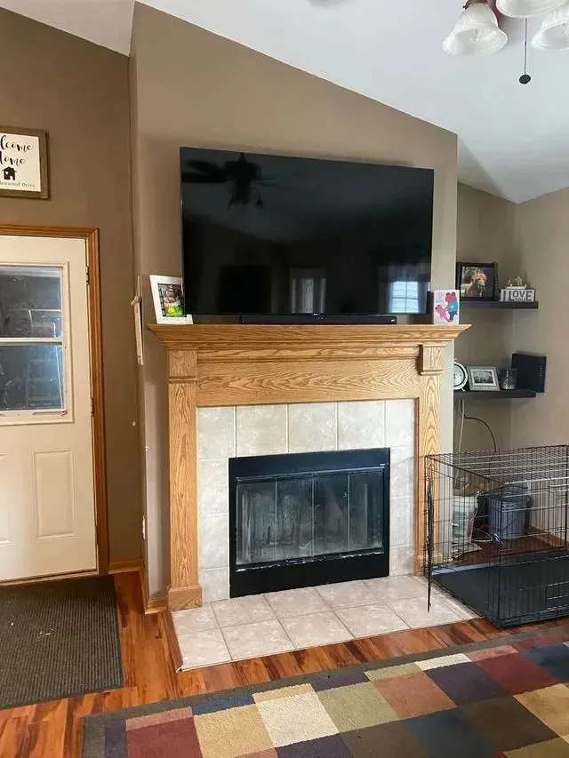 Fireplace with a large TV above, flanked by brown walls, a doorway, and shelves.