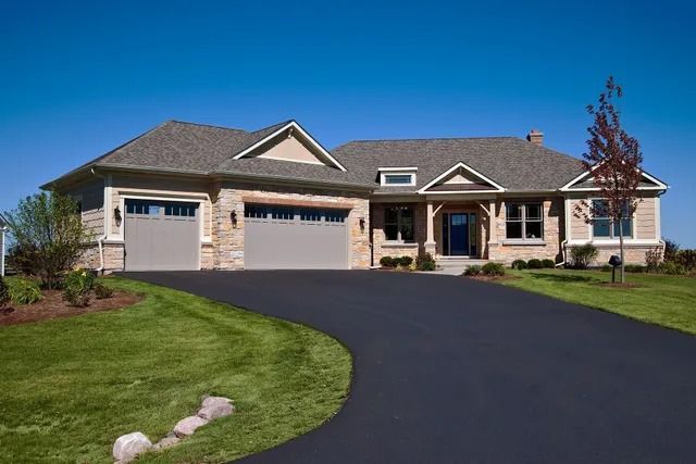 Brick and stone entrance pillars with concrete tops, set against trees and a blue sky.