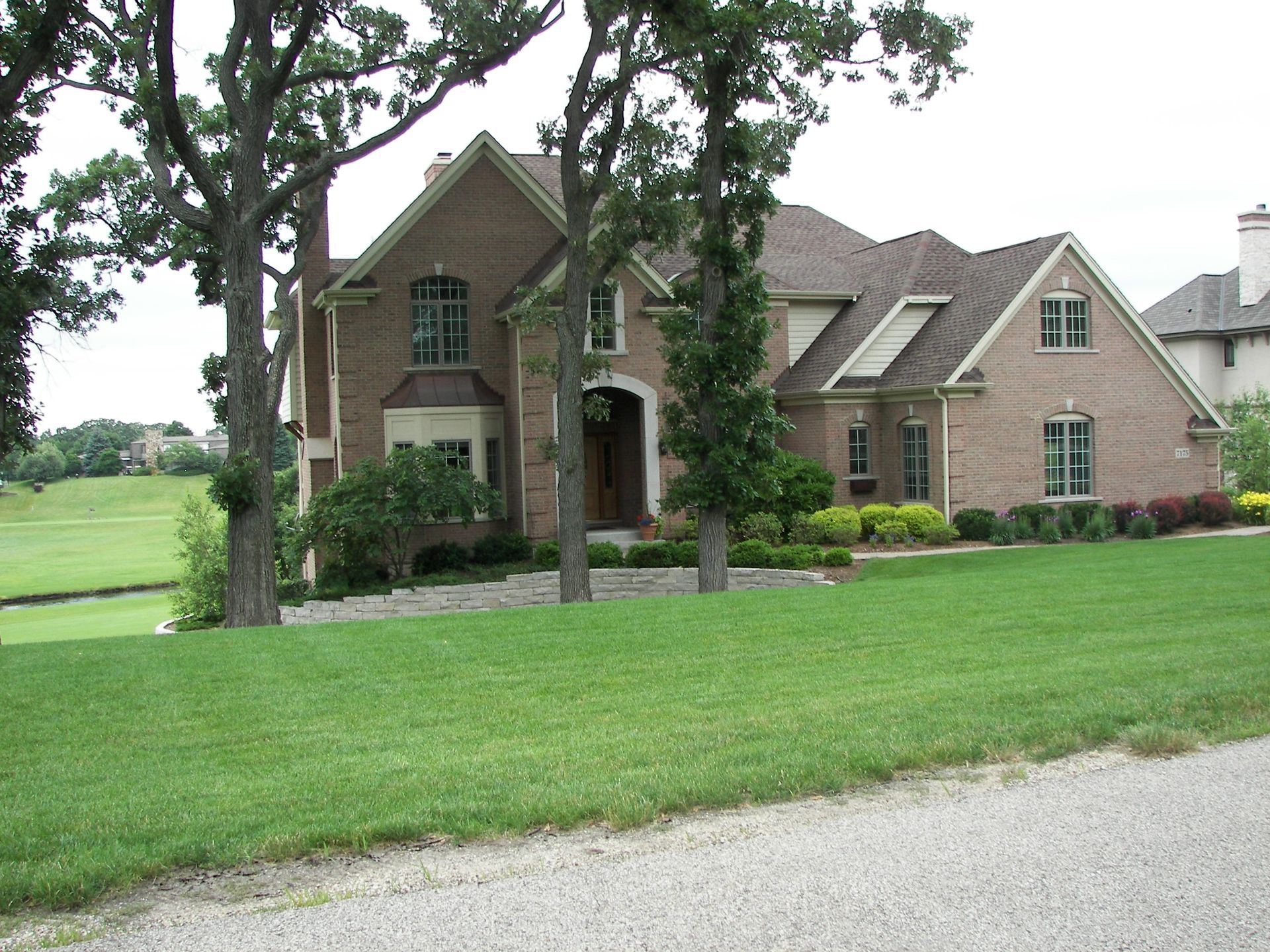 Brick house with trees and green lawn.