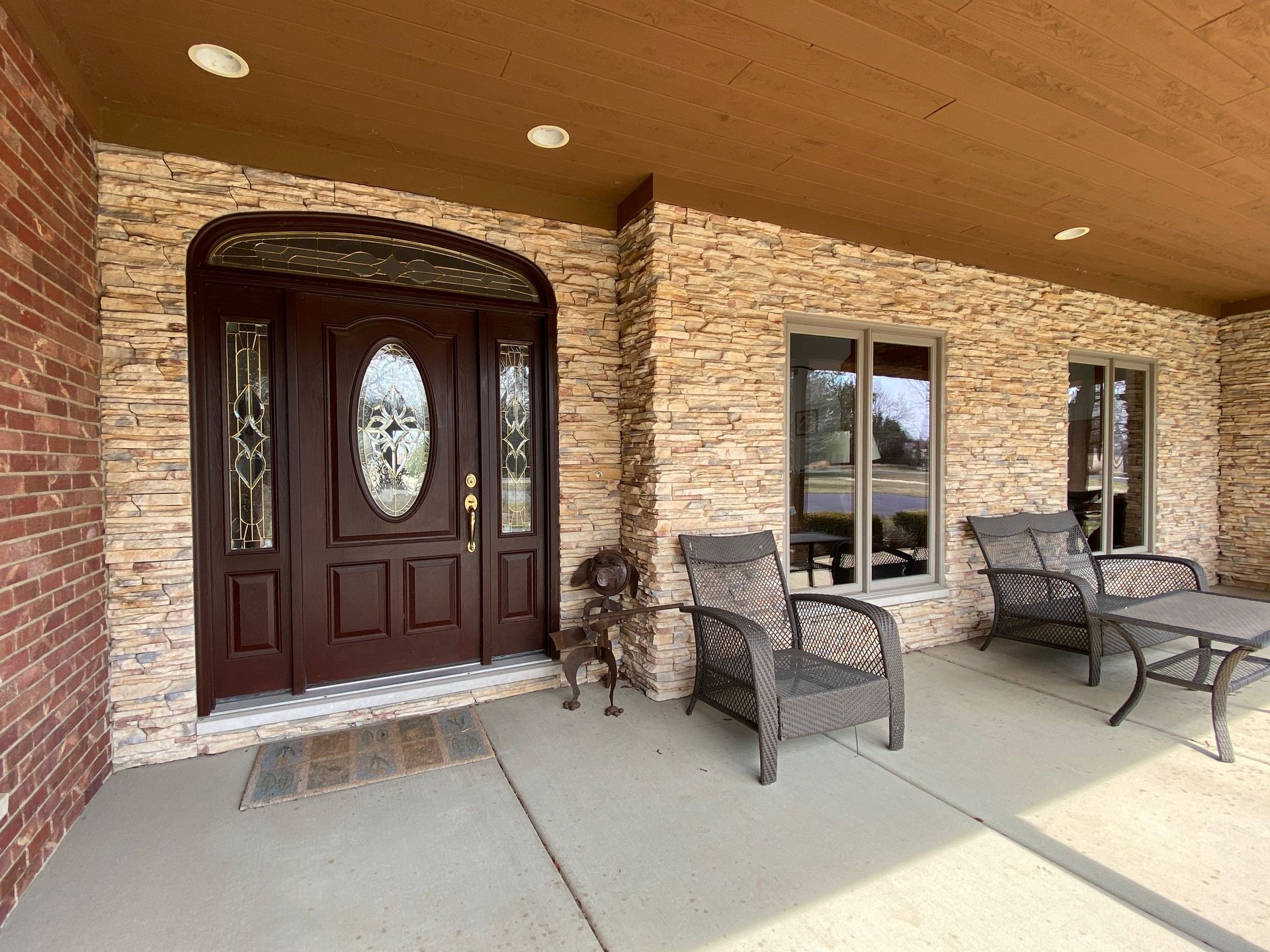 Entryway with brown door, stone wall, chairs, and small dog.