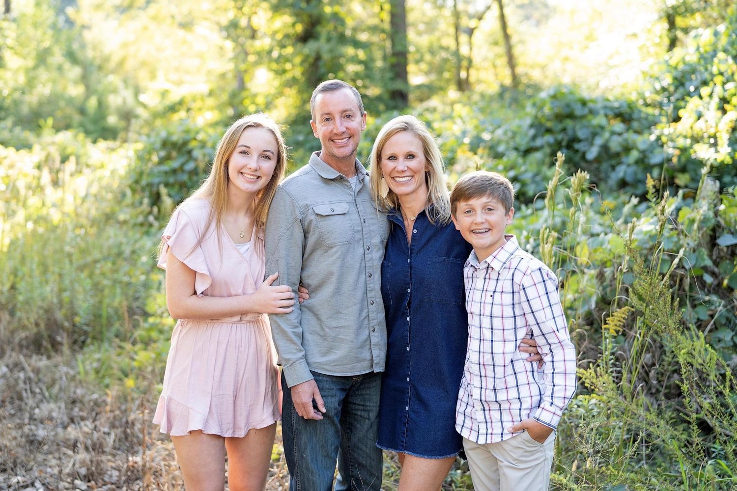 A family is posing for a picture in the woods.