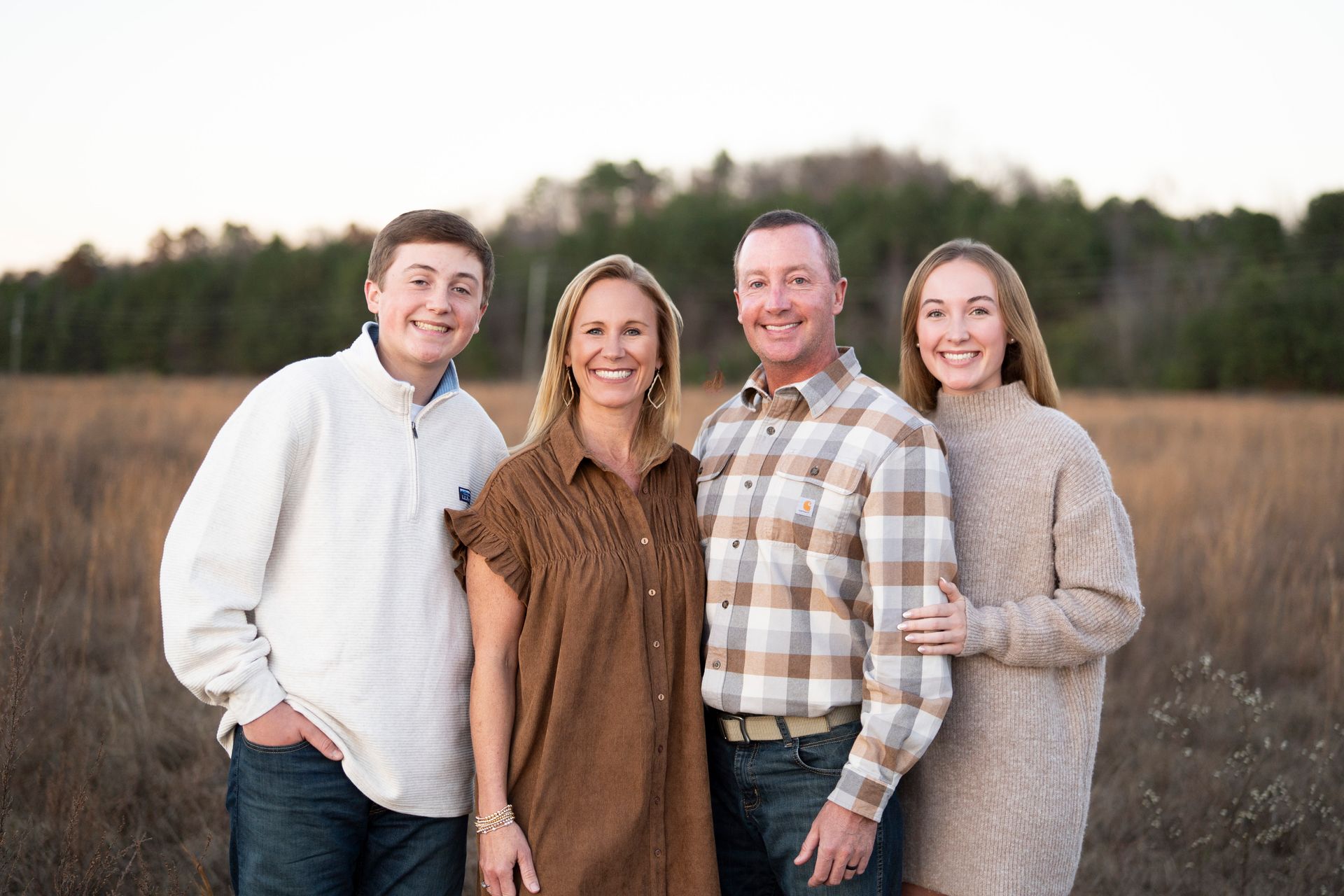 A family is posing for a picture in the fields.