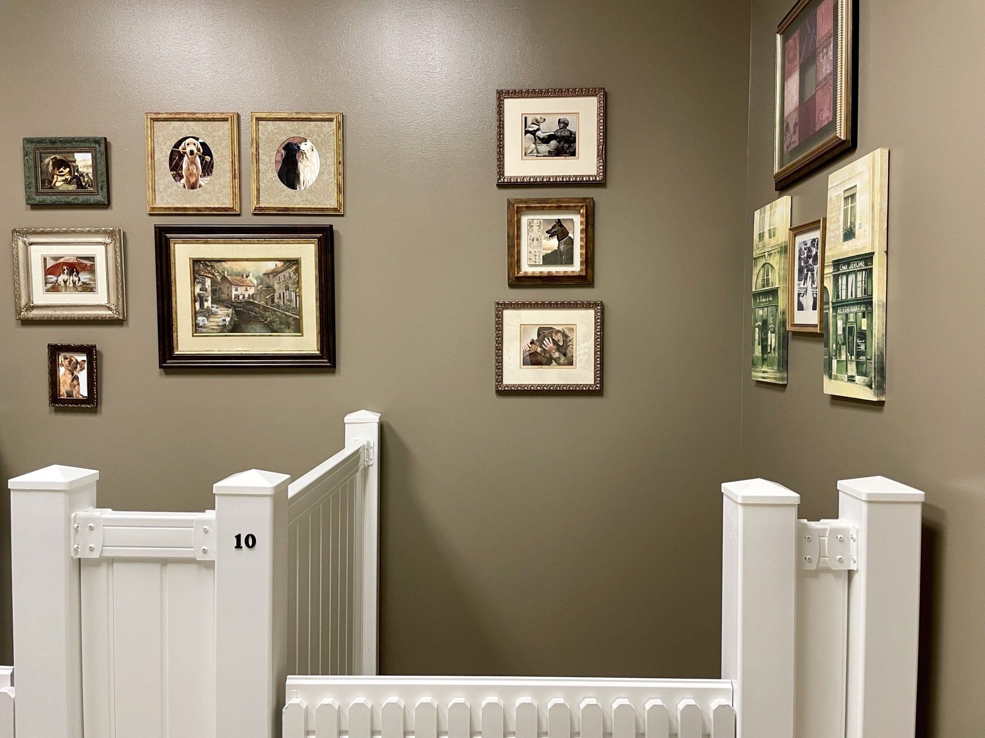A room with pictures on the wall and a white fence