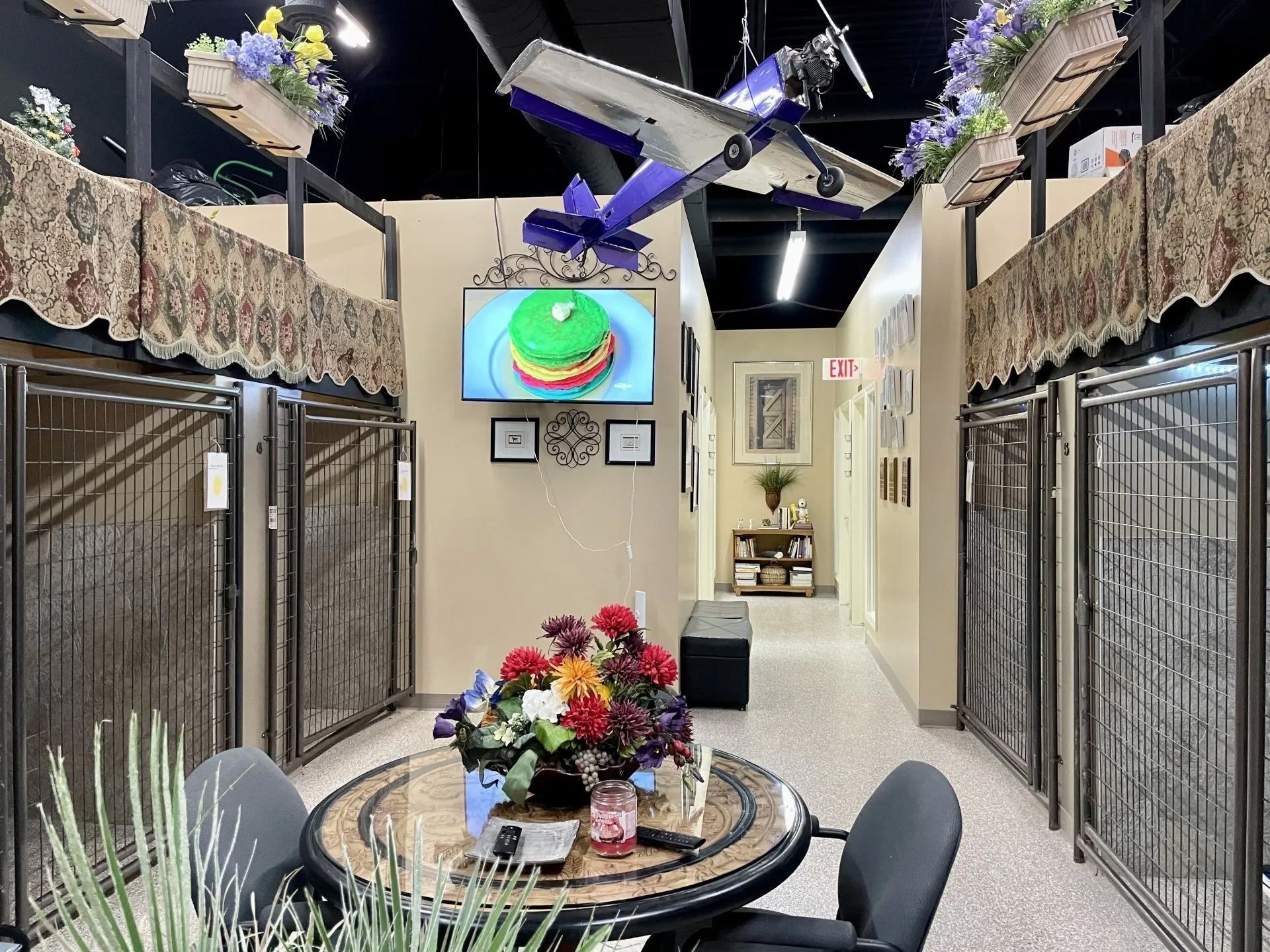 A room with a table and chairs and a television on the wall.