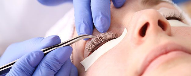 A woman is getting her eyelashes done at a beauty salon