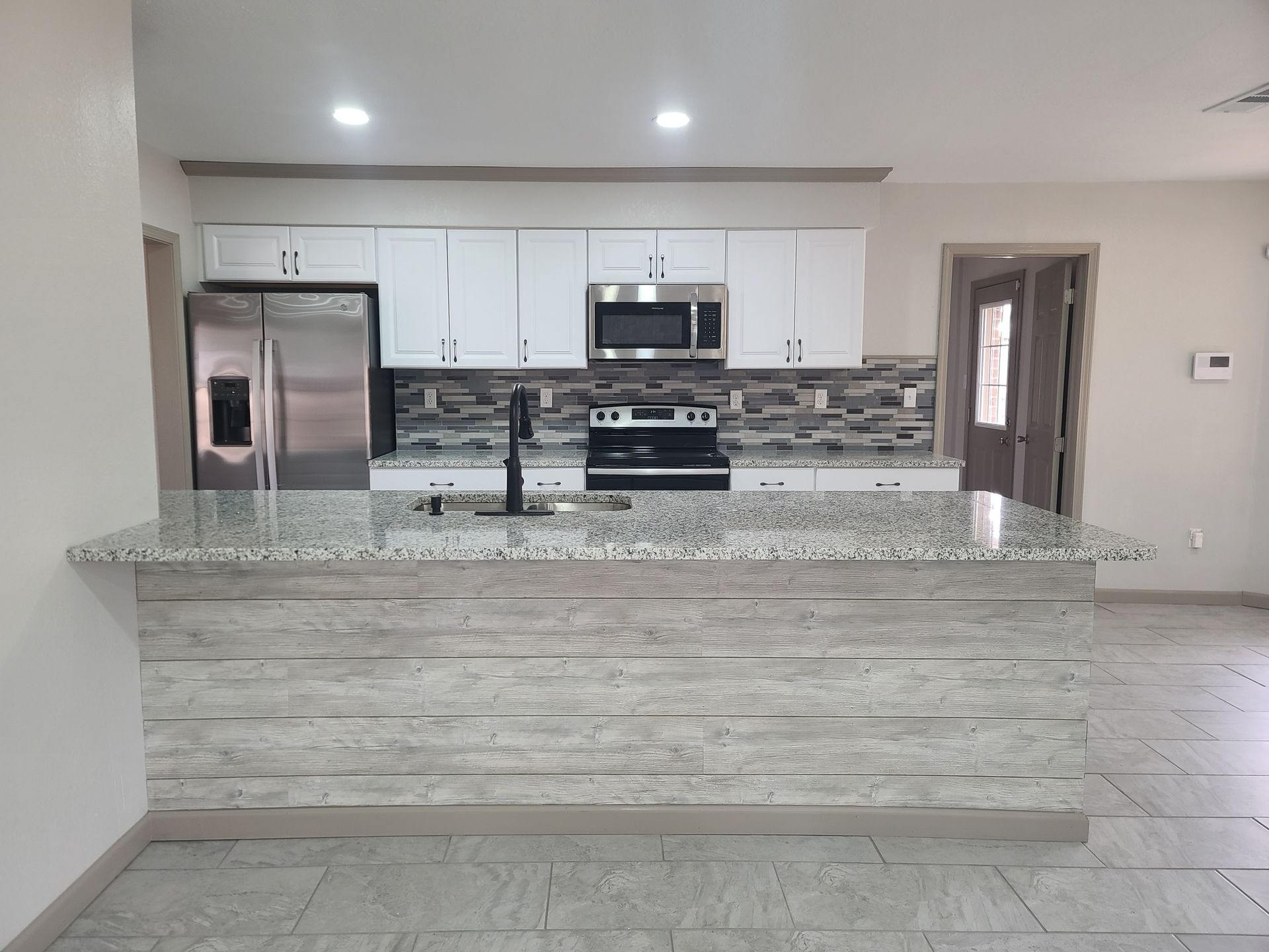 A kitchen with granite counter tops , stainless steel appliances , and white cabinets.