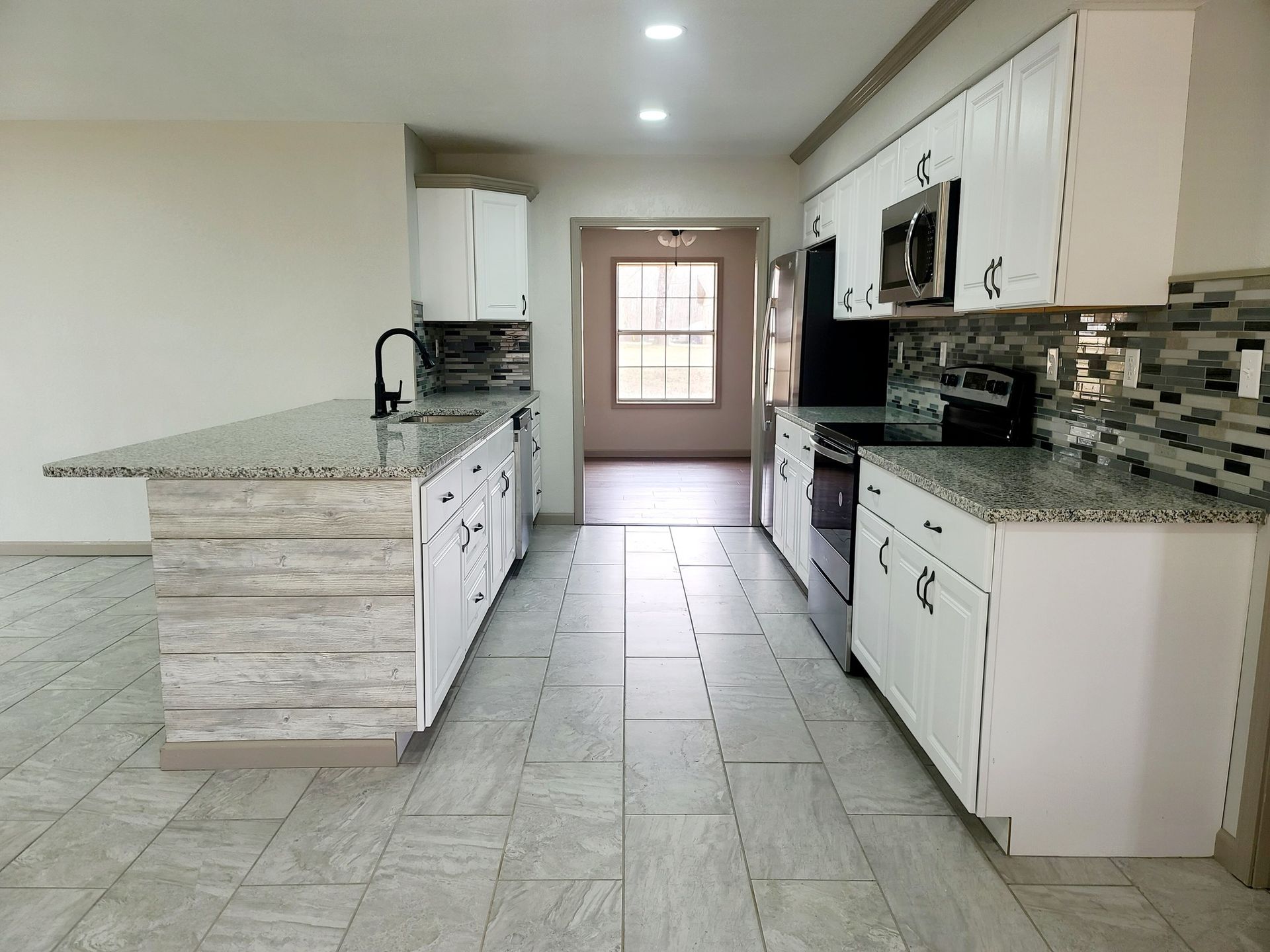 An empty kitchen with white cabinets and granite counter tops