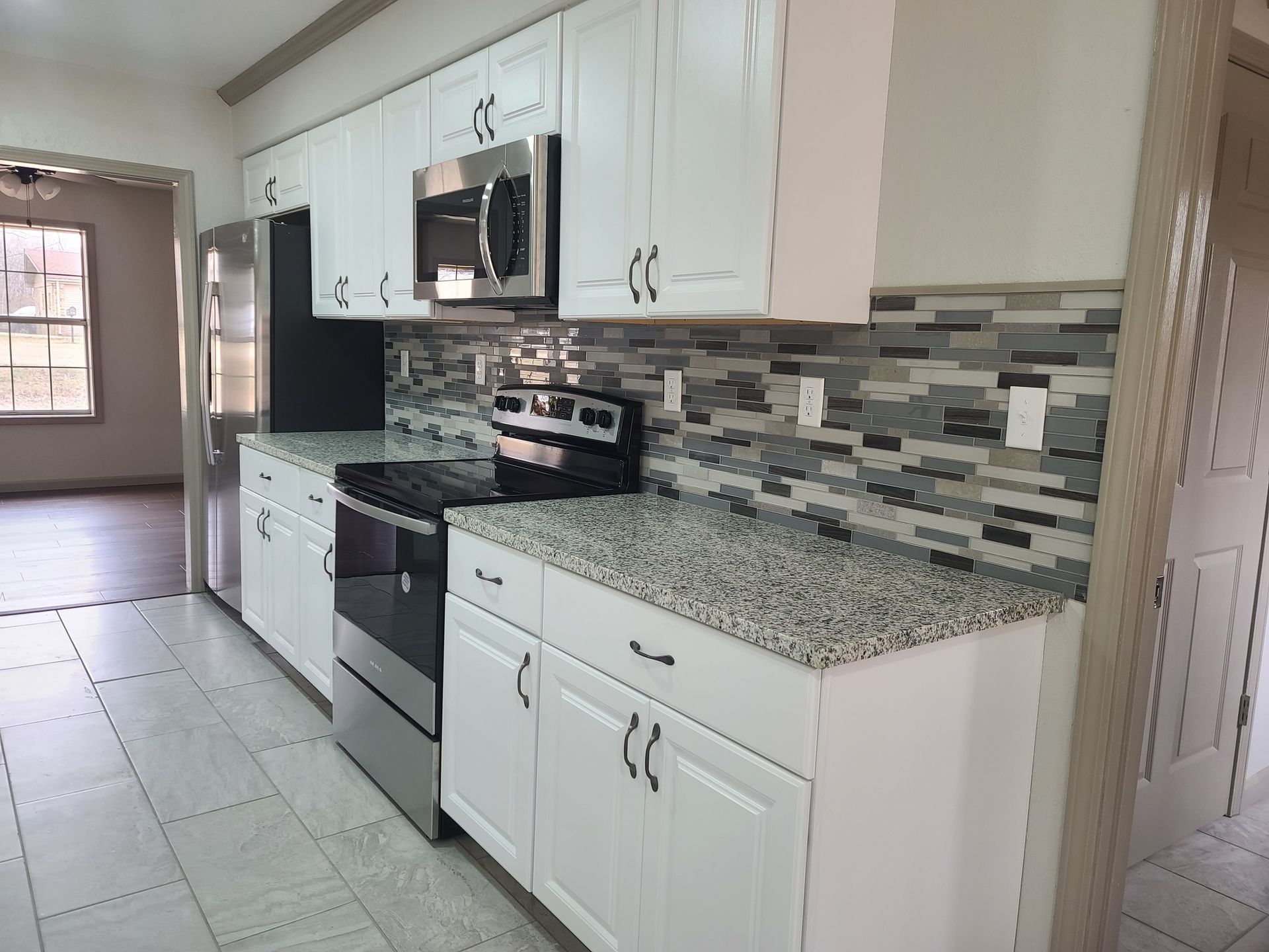 A kitchen with white cabinets , stainless steel appliances and granite counter tops.