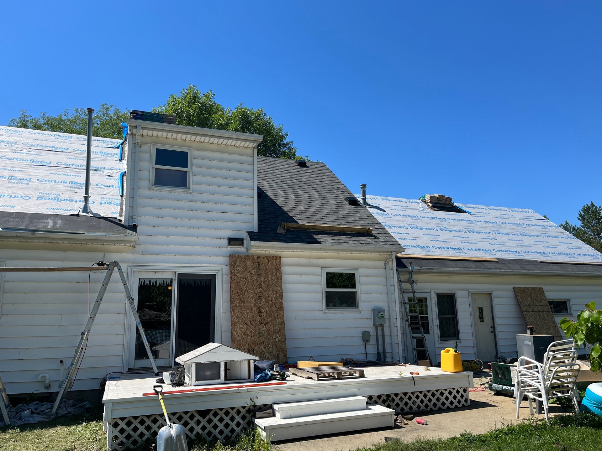 a white house with a roof that is being remodeled
