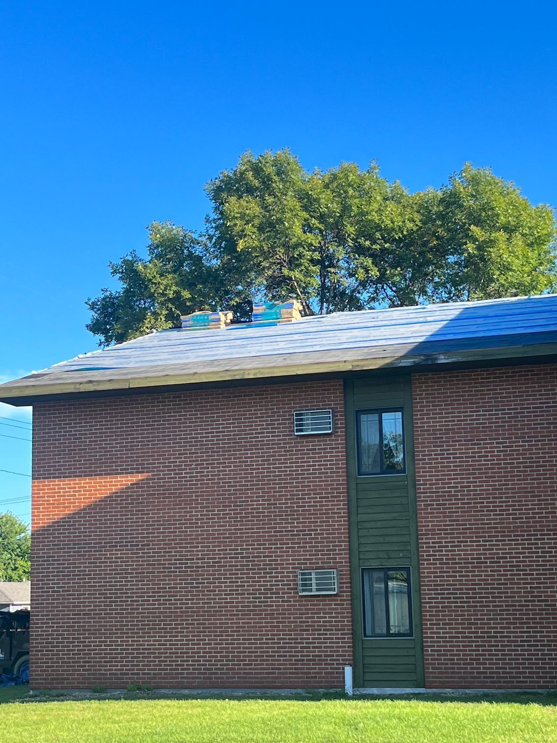 a brick building with a green door and a blue sky in the background