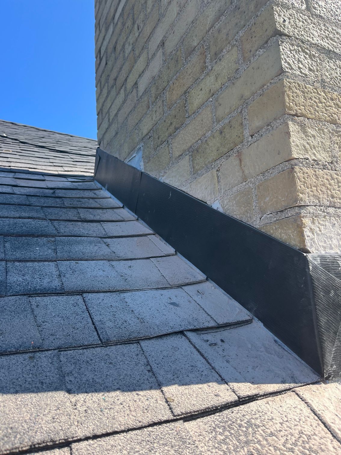 a close up of a roof with a chimney in the background