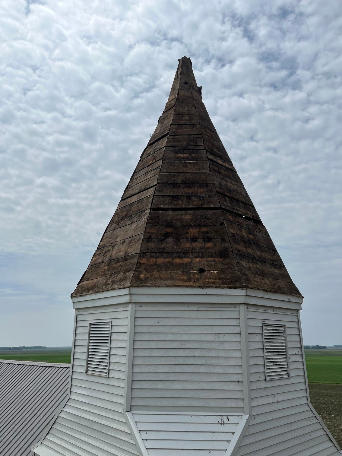 a church steeple with a wooden roof and a cloudy sky in the background