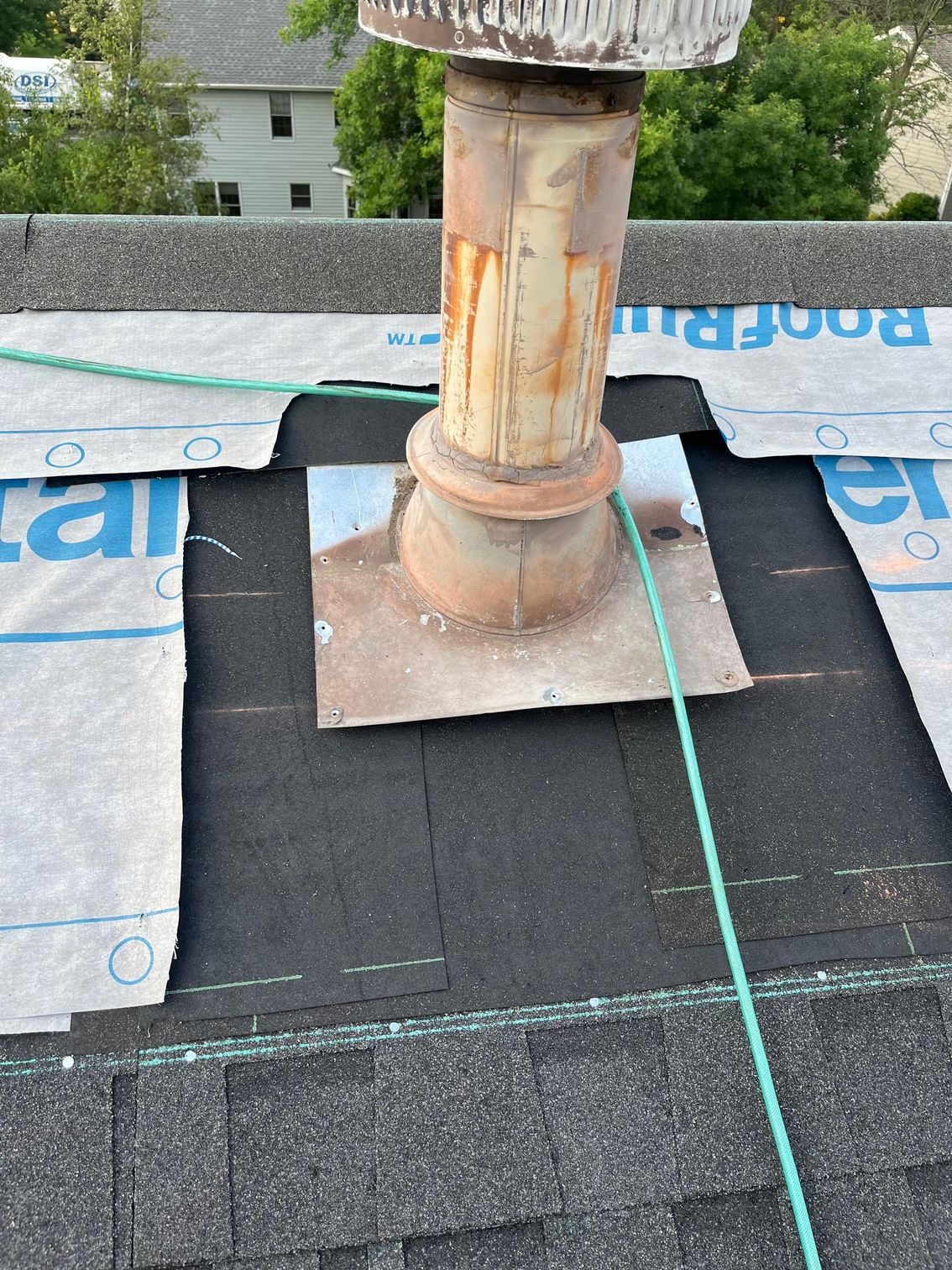 a chimney on top of a roof with a green hose attached to it