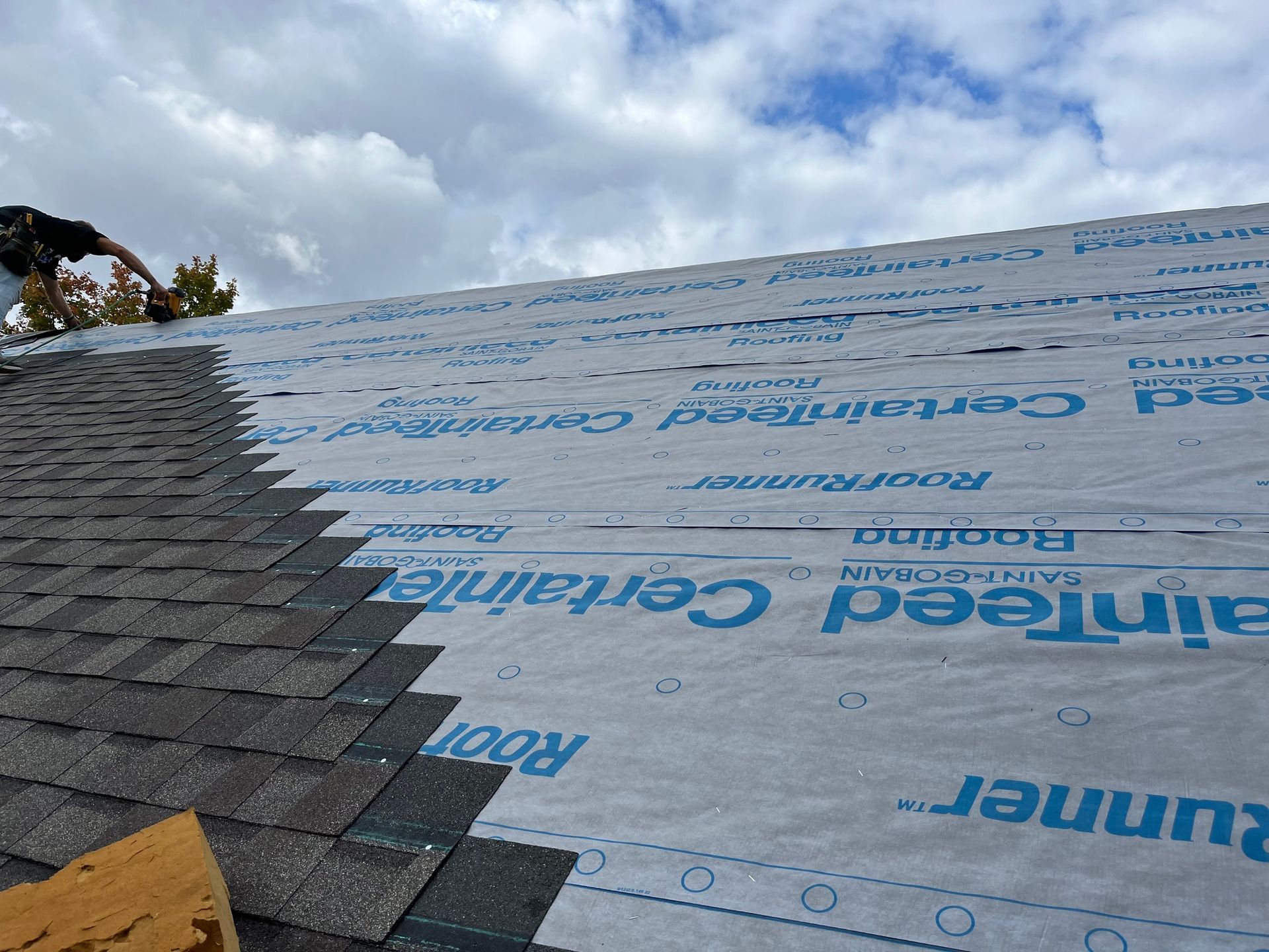 a man is standing on top of a roof covered in shingles