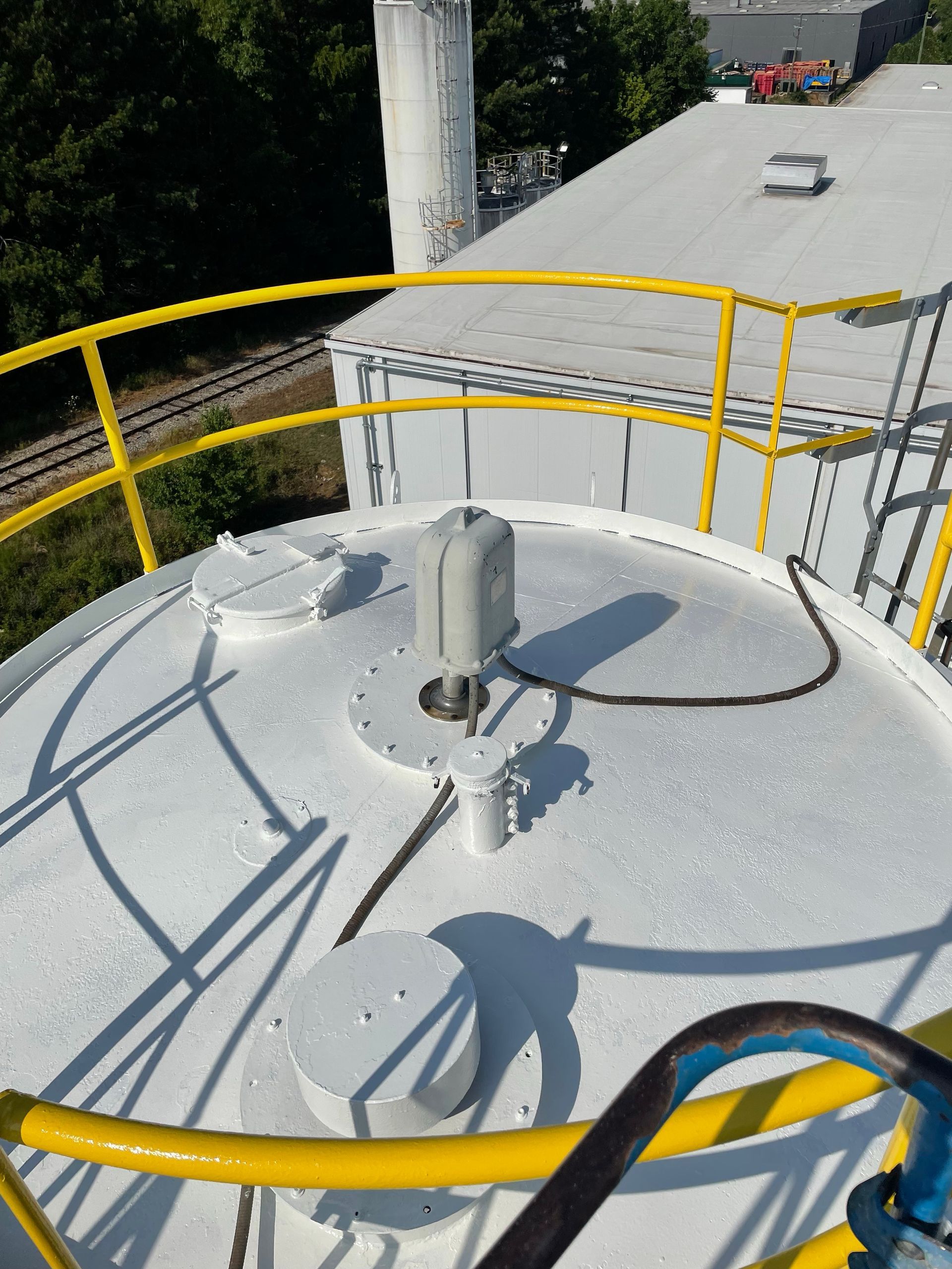 Yellow-railed rooftop tank with a gray hatch and shadows in bright sunlight