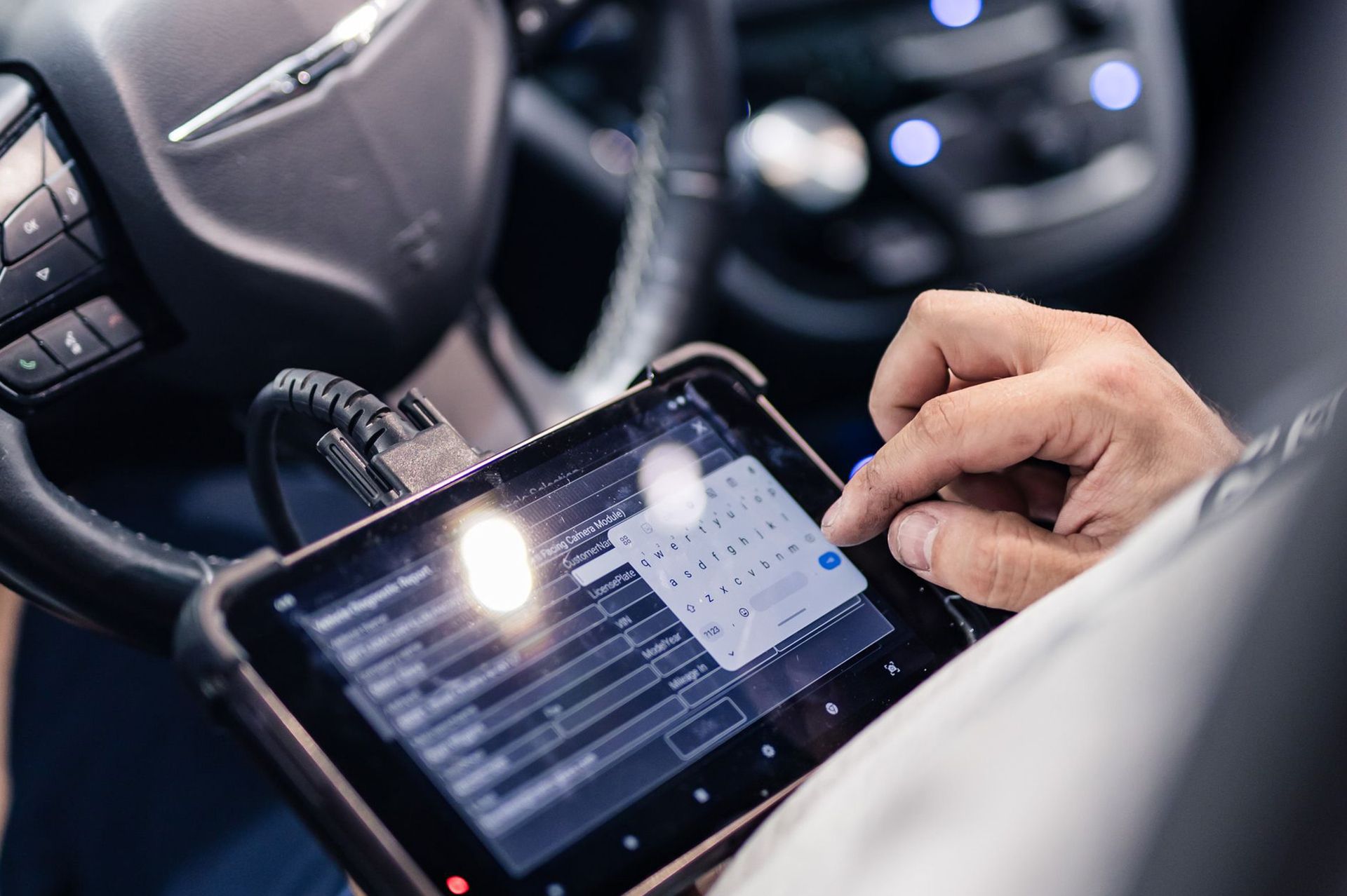 Person using a diagnostic tablet inside a car to check the vehicle's systems.