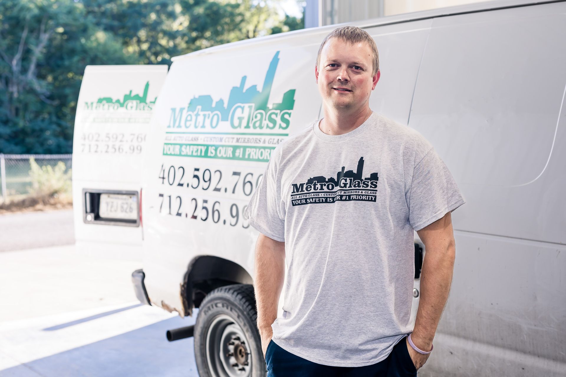 A man in a grey shirt stands in front of a white van with 